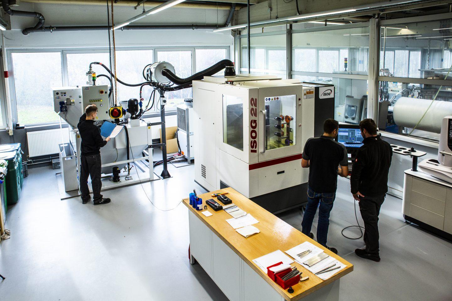 Blick in den Werkzeugbau bei HORA eTec in Bünde mit drei Mitarbeitern an den Maschinen